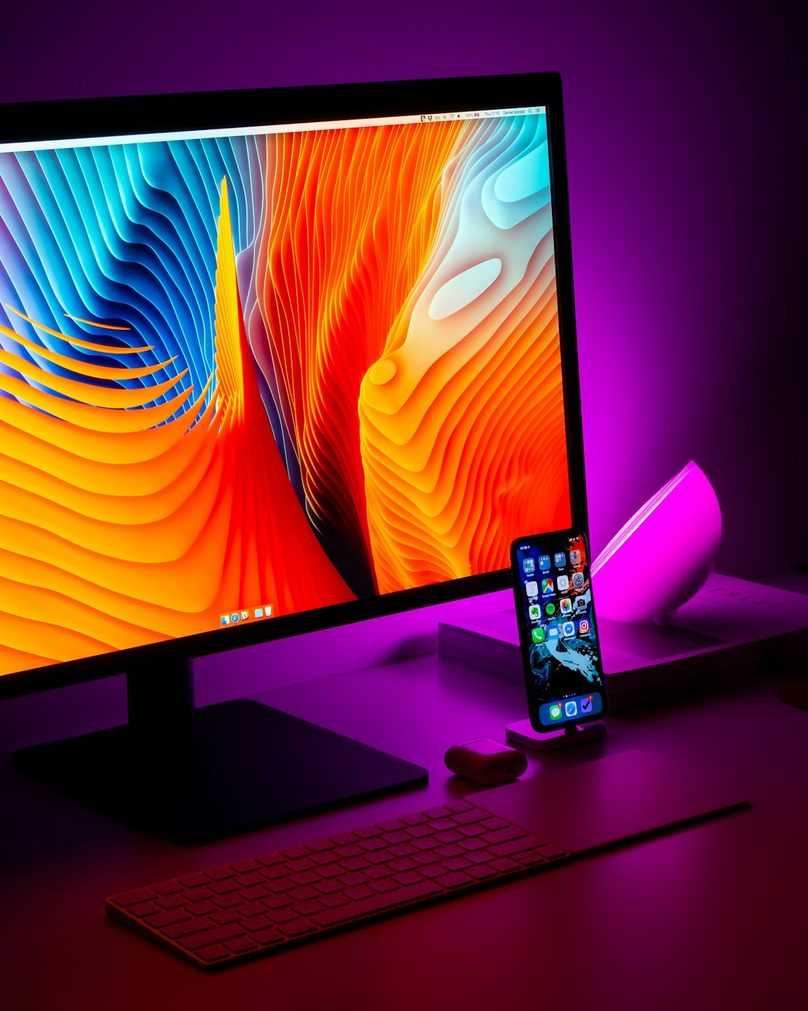 Moderner Desktop-Computer mit abstraktem Hintergrundbild und pinker Lampe.
