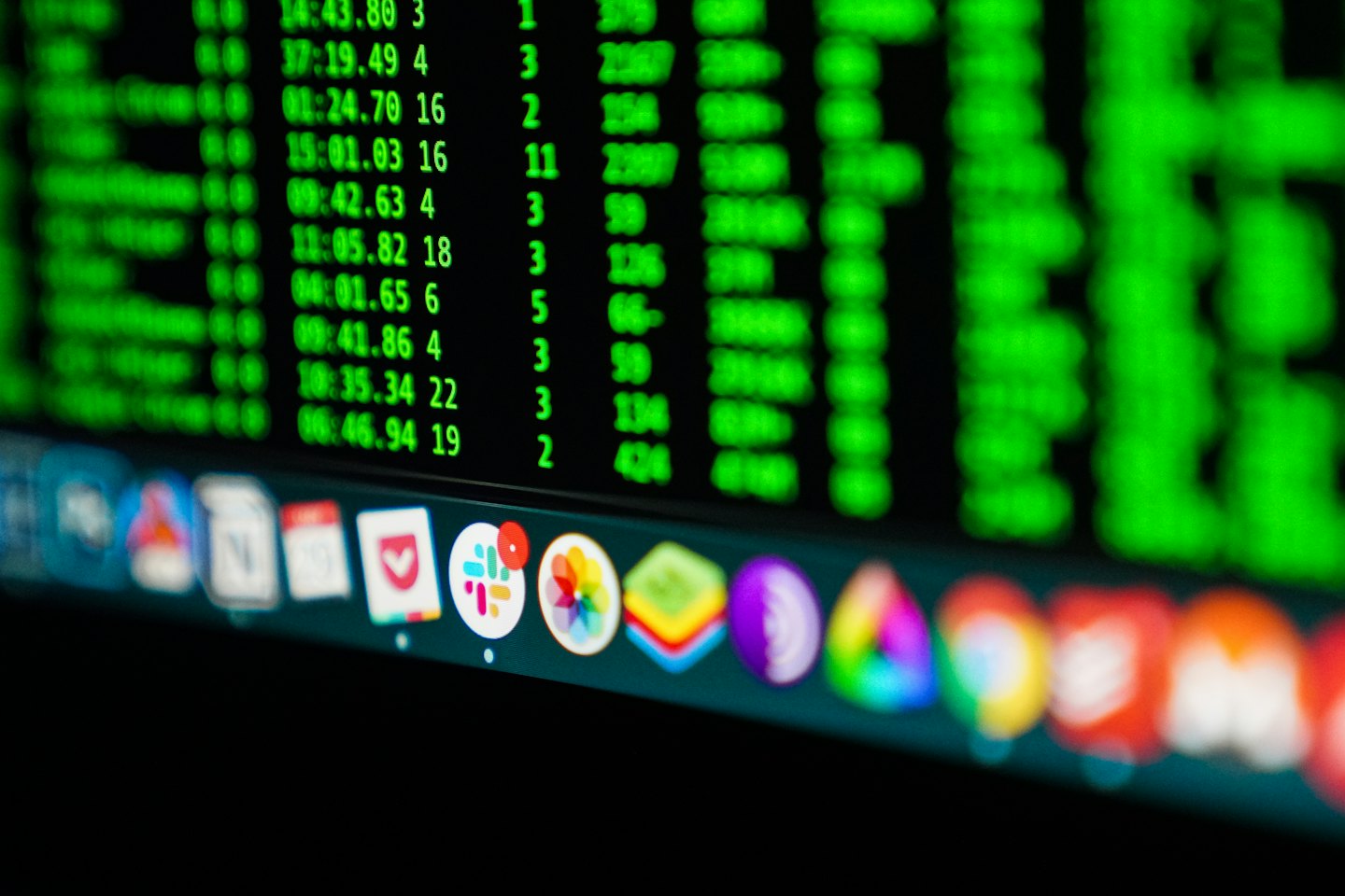 Computerbildschirm zeigt hellgrünen Code und bunte Anwendungssymbole.