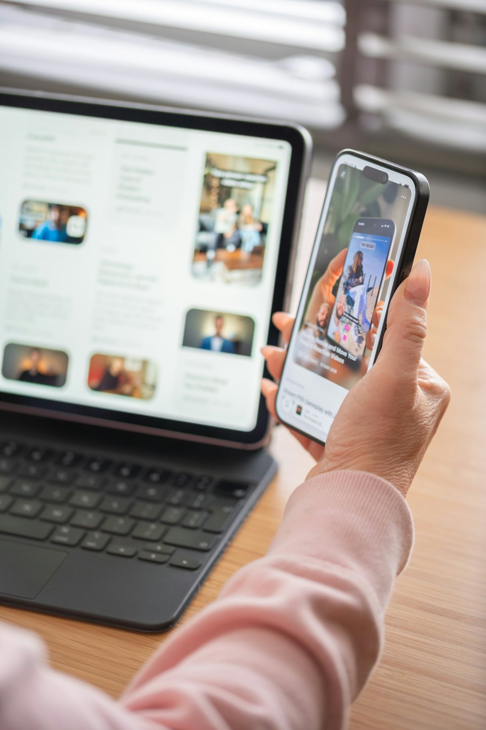 Eine Person benutzt ein Smartphone, während ein Tablet auf dem Tisch liegt.
