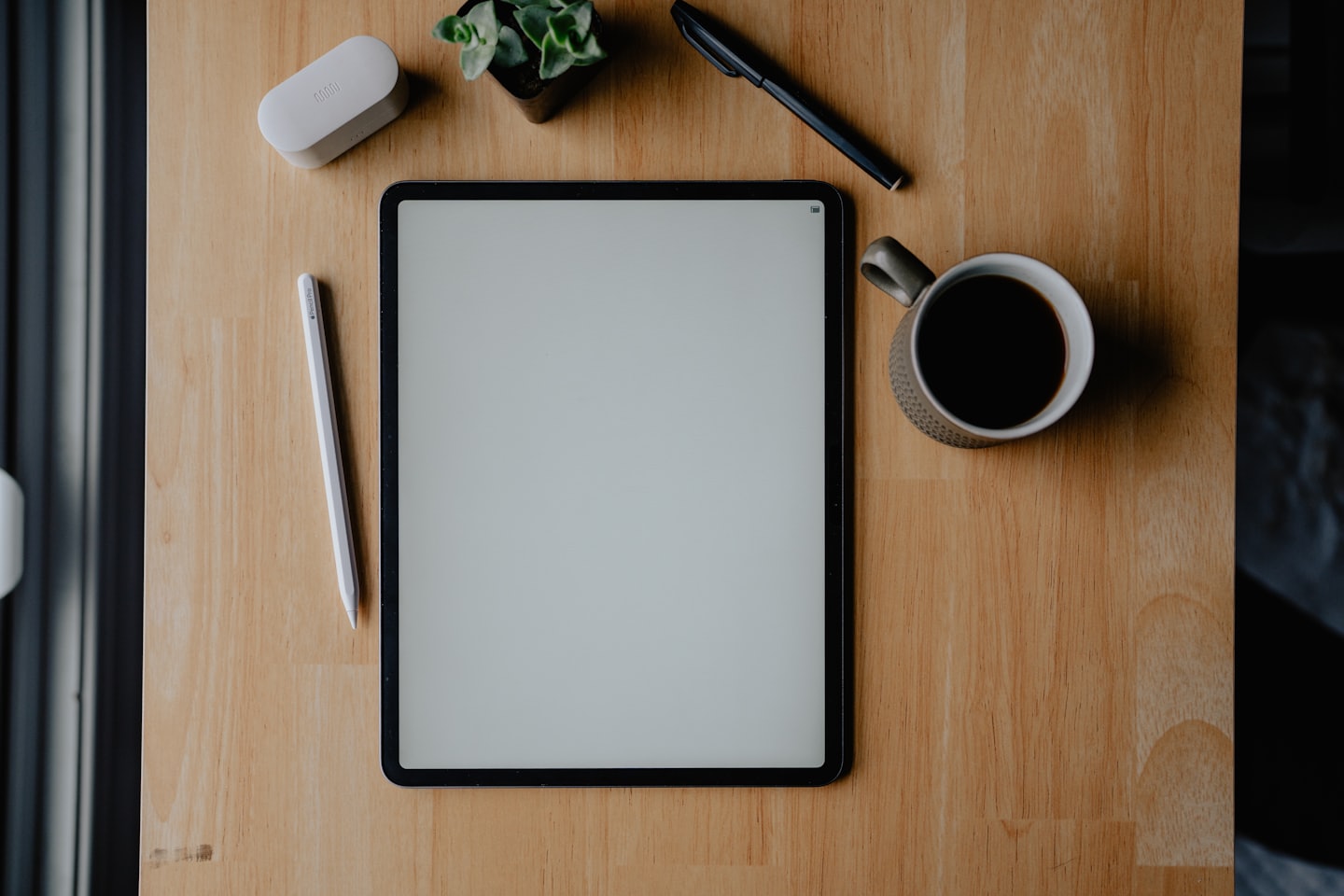 Tablet und Büromaterial auf einem Holztisch.