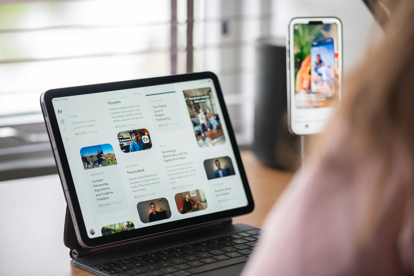 Person arbeitet drinnen an einem Tablet und Smartphone.